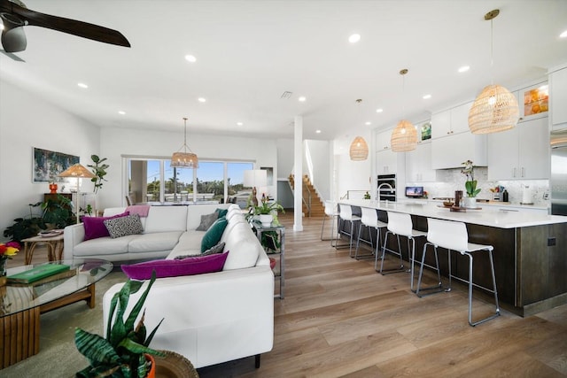 living room featuring light wood-style flooring, stairway, ceiling fan, and recessed lighting