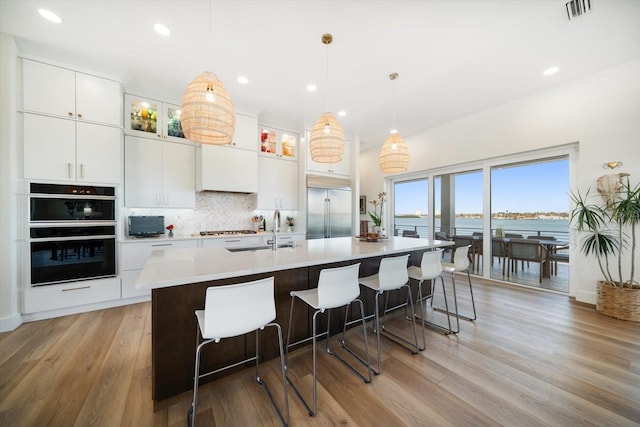 kitchen with dobule oven black, tasteful backsplash, visible vents, stainless steel built in fridge, and a sink