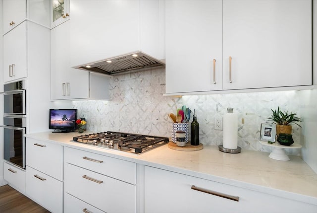 kitchen with stainless steel appliances, custom range hood, backsplash, and white cabinetry