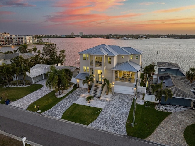 view of front facade featuring a water view, a standing seam roof, metal roof, a balcony, and stairs