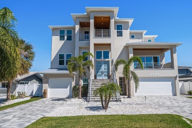 modern home with a standing seam roof, an attached garage, and stucco siding