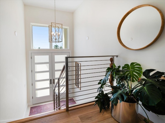 foyer with french doors, wood finished floors, and an inviting chandelier