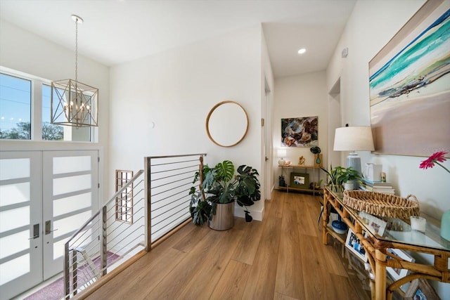 hall featuring light wood-type flooring, recessed lighting, an upstairs landing, and an inviting chandelier