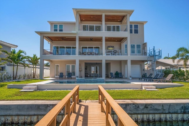 rear view of property featuring a ceiling fan, a patio area, a balcony, and stucco siding