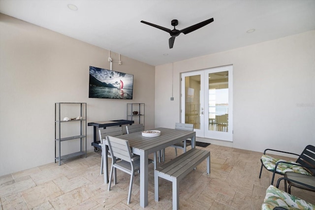 dining space with a ceiling fan, stone tile flooring, and french doors