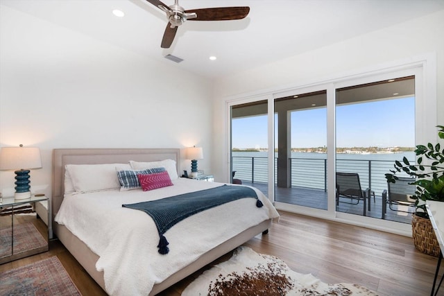 bedroom featuring visible vents, wood finished floors, a water view, access to exterior, and recessed lighting