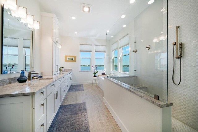 full bath featuring double vanity, recessed lighting, a sink, wood finished floors, and walk in shower