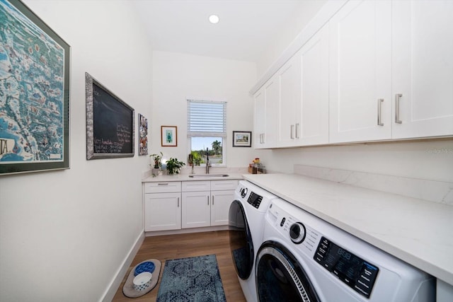 laundry room with a sink, wood finished floors, baseboards, cabinet space, and washing machine and clothes dryer