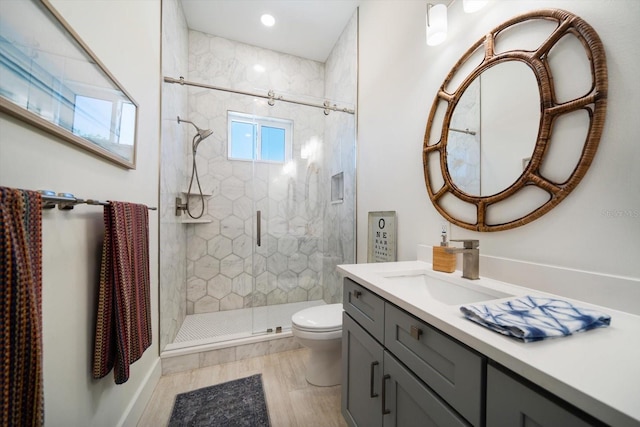 bathroom with toilet, a shower stall, wood finished floors, and vanity