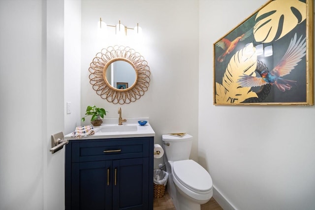 half bathroom featuring vanity, toilet, and baseboards