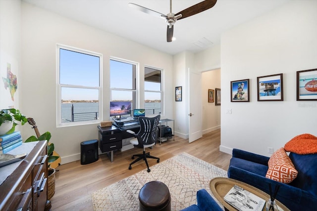 home office featuring light wood-style floors, visible vents, baseboards, and a ceiling fan