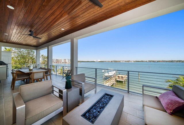 exterior space featuring a water view, outdoor dining area, a ceiling fan, and an outdoor living space with a fire pit