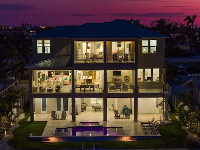 rear view of house with a patio, a balcony, and stucco siding