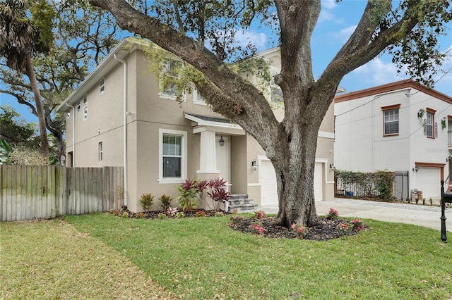 view of front of property with stucco siding, a front lawn, fence, concrete driveway, and a garage