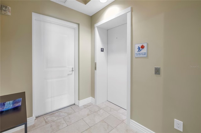 hallway with baseboards and elevator