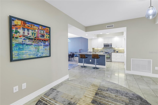 corridor with light tile patterned floors, baseboards, and visible vents