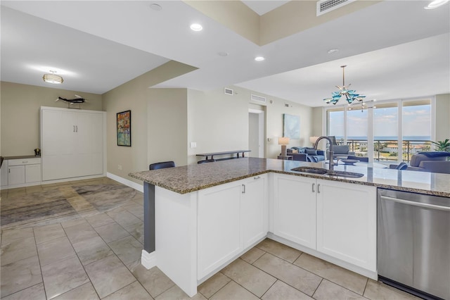 kitchen featuring stone counters, a sink, visible vents, open floor plan, and stainless steel dishwasher