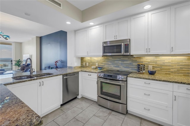 kitchen with appliances with stainless steel finishes, white cabinetry, a sink, and tasteful backsplash