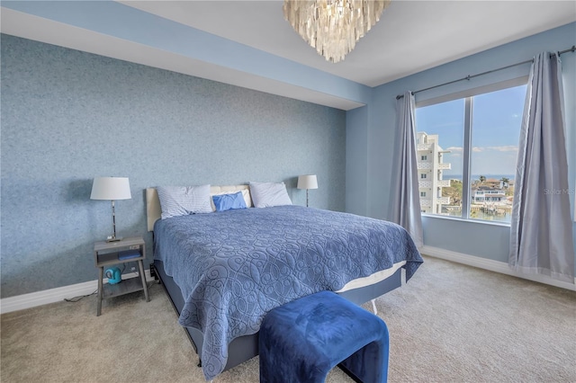 carpeted bedroom featuring an inviting chandelier, baseboards, and wallpapered walls