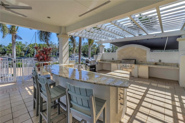 view of patio with a grill, fence, a pergola, and exterior kitchen