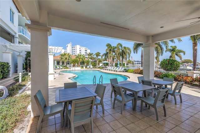 view of patio / terrace with a community pool, fence, and outdoor dining space