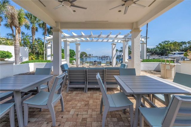 view of patio featuring outdoor dining space, a water view, ceiling fan, and a pergola