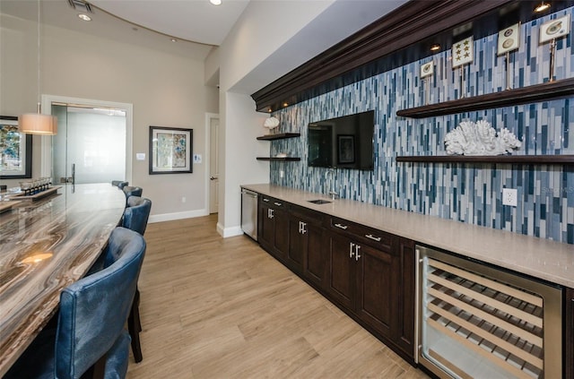 bar with baseboards, dishwasher, light wood-style flooring, wine cooler, and a sink