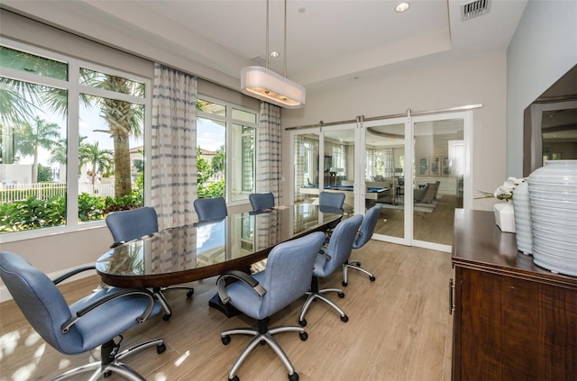 office area featuring light wood-style floors, a raised ceiling, and visible vents