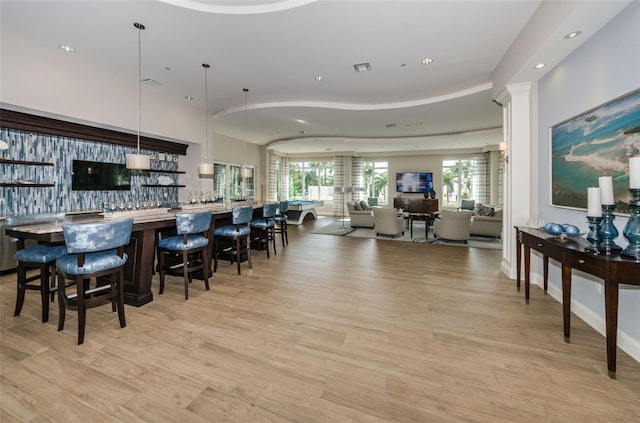 interior space with recessed lighting, baseboards, hanging light fixtures, light wood-type flooring, and a kitchen breakfast bar