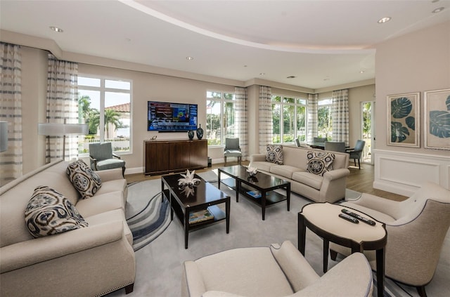 living area with recessed lighting, wainscoting, a decorative wall, and light wood finished floors