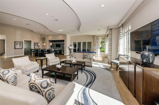 living room with recessed lighting, visible vents, and light wood finished floors