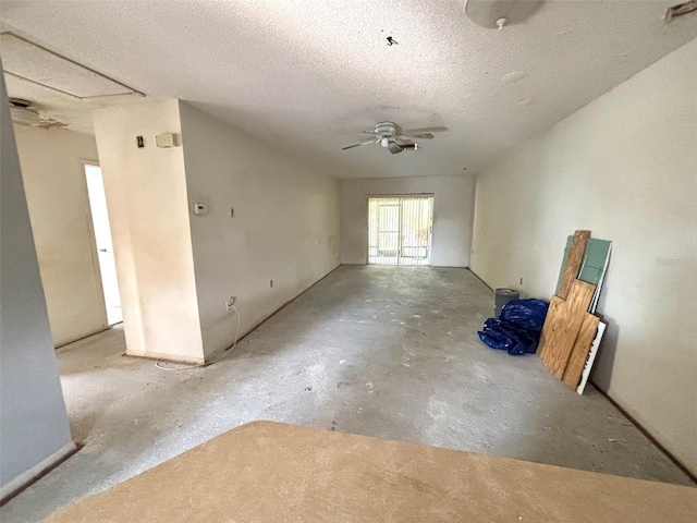 spare room with a textured ceiling, concrete flooring, and a ceiling fan