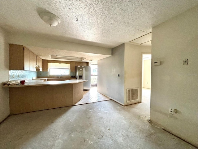 kitchen with visible vents, a sink, concrete floors, a peninsula, and stainless steel fridge with ice dispenser