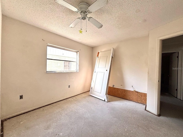 unfurnished bedroom with a textured ceiling, concrete floors, and a ceiling fan