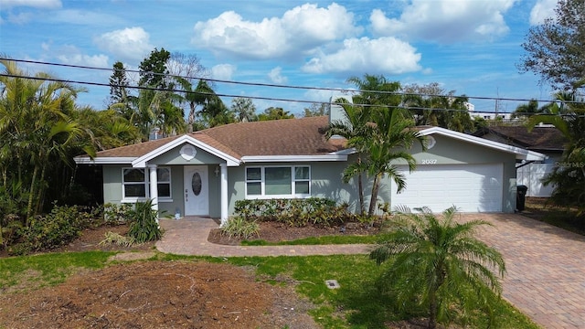 ranch-style home with a garage, decorative driveway, and stucco siding