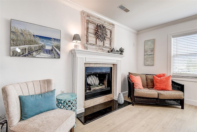 living area featuring ornamental molding, a fireplace, wood finished floors, and visible vents