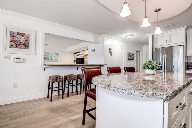 kitchen featuring light wood finished floors, stainless steel fridge with ice dispenser, ornamental molding, a kitchen breakfast bar, and light stone counters