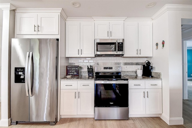 kitchen with light stone counters, stainless steel appliances, white cabinets, light wood finished floors, and tasteful backsplash