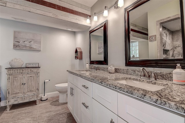 full bathroom with baseboards, a sink, toilet, and double vanity