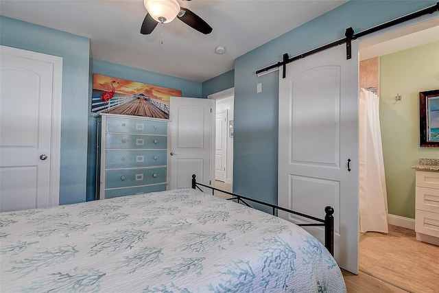 bedroom featuring a barn door, baseboards, and ceiling fan