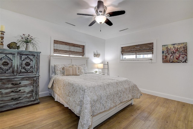 bedroom with baseboards, visible vents, ceiling fan, and wood finished floors