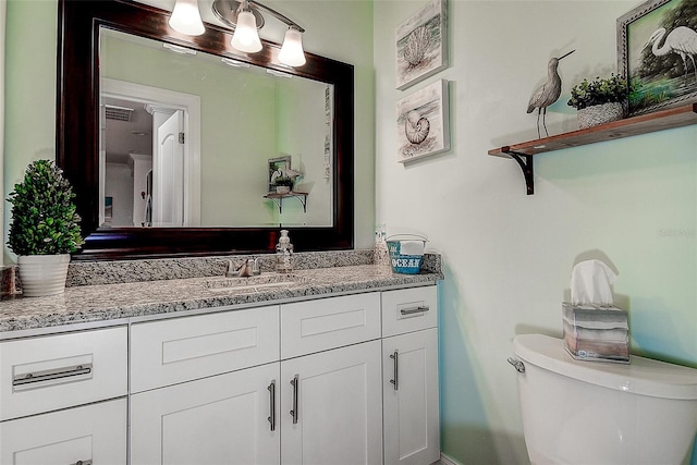 half bathroom with toilet, visible vents, and vanity