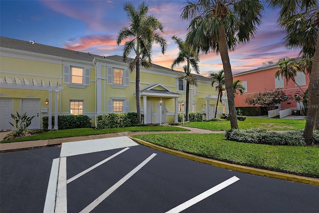 view of front of house featuring a front yard, uncovered parking, and stucco siding