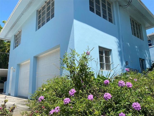 view of side of home featuring a garage and stucco siding