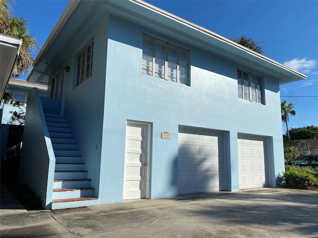 view of home's exterior featuring stairway, a garage, driveway, and stucco siding