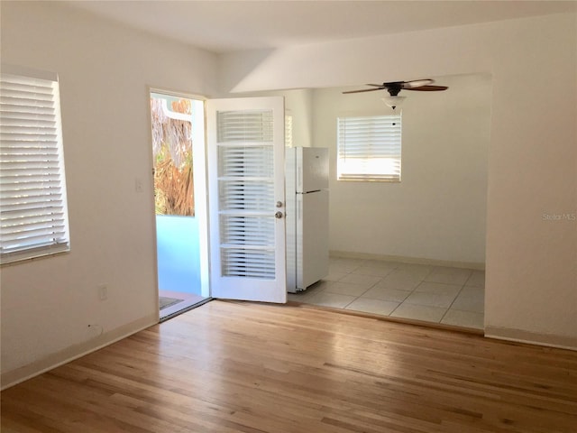 unfurnished room with a ceiling fan, baseboards, and light wood finished floors