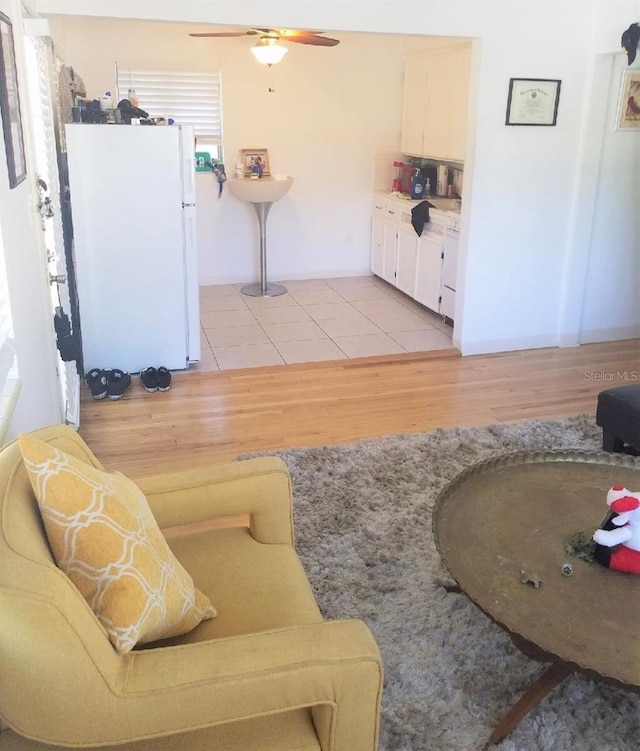 living area featuring light wood-style flooring and a ceiling fan