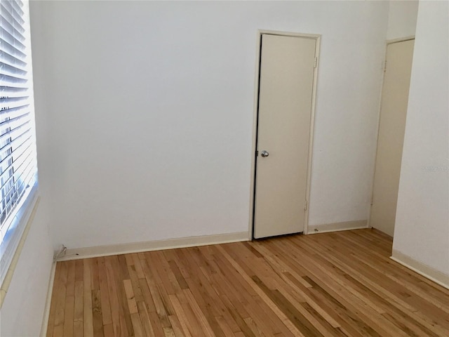 spare room with baseboards, light wood-type flooring, and a wealth of natural light