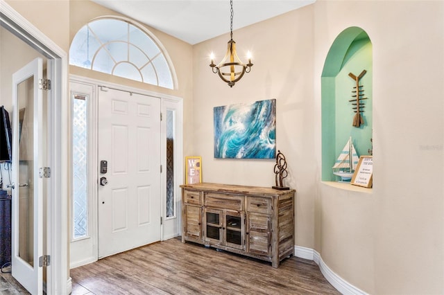 entrance foyer with baseboards, a chandelier, and wood finished floors