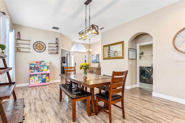 dining area with arched walkways, light wood-style flooring, separate washer and dryer, visible vents, and baseboards